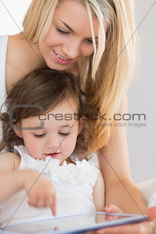 Mother and young daughter using digital tablet