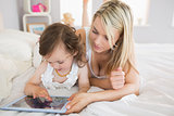 Mother and daughter using digital tablet on bed