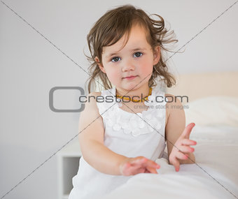 Portrait of cute little girl sitting on bed