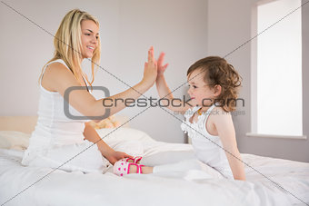 Mother and daughter high fiving on bed