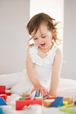 Cute girl playing with building blocks on bed