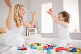 Mother and daughter playing with building blocks on bed