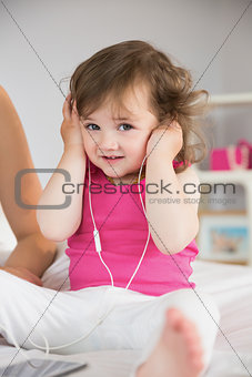 Cute little girl listening to music on bed