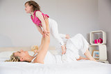 Young woman playing with daughter in bed