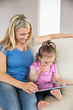 Mother and daughter using digital tablet on couch