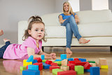 Girl playing with building blocks while mother on conch