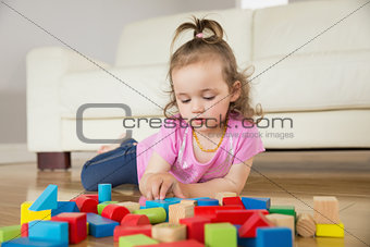 Girl playing with building blocks on floor
