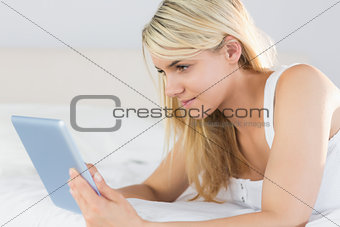 Relaxed beautiful woman using digital tablet in bed