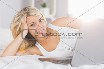 Relaxed beautiful woman using laptop in bed