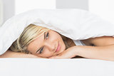 Thoughtful relaxed woman lying in bed