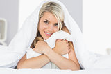 Smiling relaxed young woman hugging pillow in bed