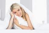Smiling relaxed young woman hugging pillow in bed