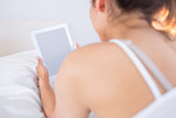 Relaxed woman using digital tablet in bed