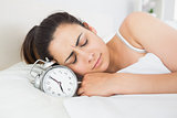 Beautiful woman sleeping in bed with alarm clock