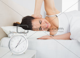 Sleepy woman covering ear with hand in bed
