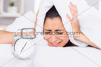Woman covering ears with sheet in bed