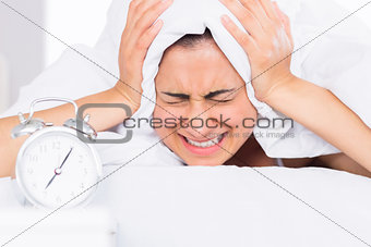 Woman covering ears with sheet in bed