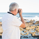 Casual mature man taking a photo of the sea