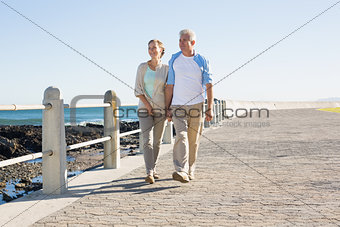 Happy casual couple walking by the coast