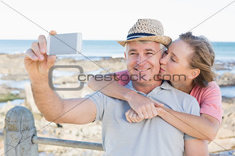 Happy casual couple taking a selfie by the coast