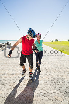 Fit mature couple rollerblading on the pier