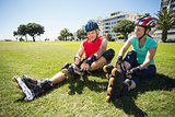 Fit mature couple tying up their roller blades on the grass