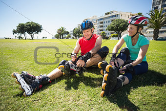 Fit mature couple tying up their roller blades on the grass