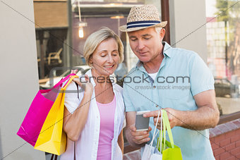Happy mature couple looking at smartphone together in the city