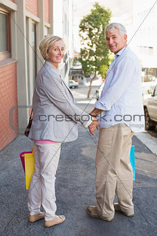 Happy mature couple walking with their shopping purchases