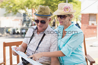 Happy tourist couple looking at map in the city