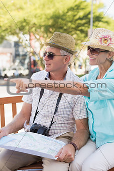 Happy tourist couple looking at map in the city