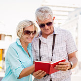 Happy tourist couple using tour guide book in the city