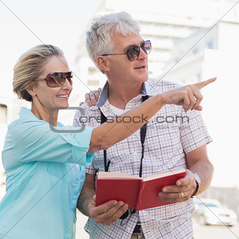 Happy tourist couple using tour guide book in the city