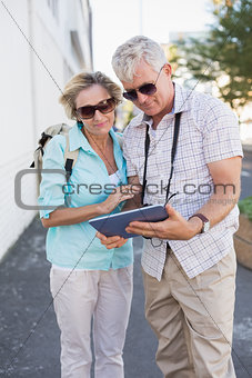 Happy tourist couple using tablet in the city