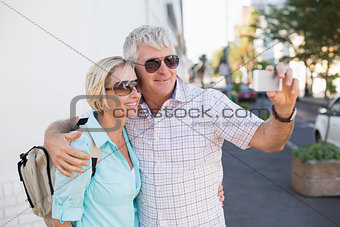 Happy tourist couple taking a selfie in the city