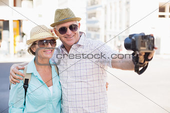 Happy tourist couple taking a selfie in the city