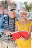 Happy tourist couple using guide book in the city