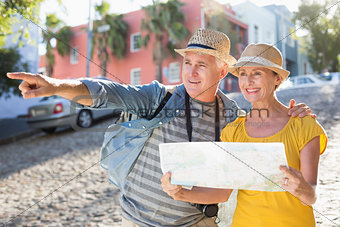 Happy tourist couple using map in the city