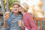 Happy mature couple drinking coffee on a bench in the city