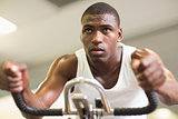 Determined man working out on exercise bike at gym