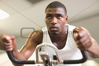 Determined man working out on exercise bike at gym