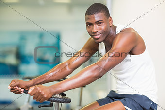 Portrait of man working out on exercise bike at gym