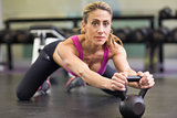 Serious woman lifting kettle bell in gym