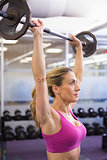 Fit young woman lifting barbell in gym