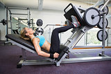 Side view of fit woman doing leg presses in gym