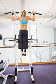 Rear view of fit woman doing pull ups at gym