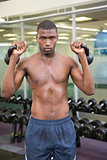 Shirtless muscular man lifting kettle bells in gym