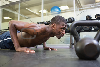 Shirtless muscular man doing push ups in gym