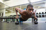 Determined man doing push ups with kettle bells in gym