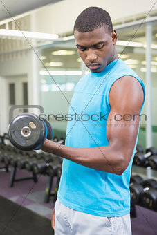 Side view of man exercising with dumbbell in gym